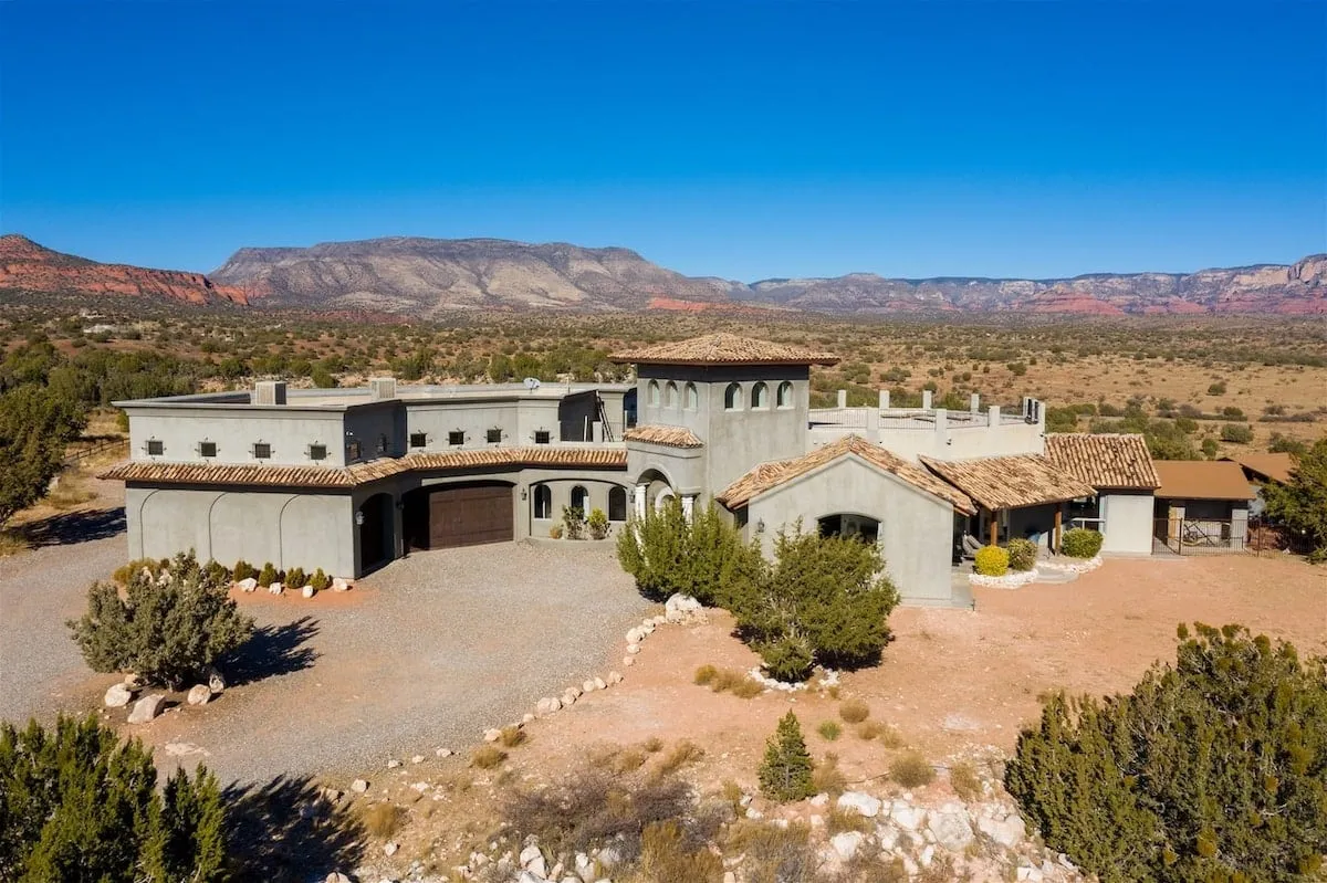 This exterior image features the adobe-style architecture of the home, nestled within Sedona's iconic landscape. The terracotta roof and surrounding natural environment evoke a sense of seclusion and tranquility, perfectly capturing the retreat’s private, serene setting.