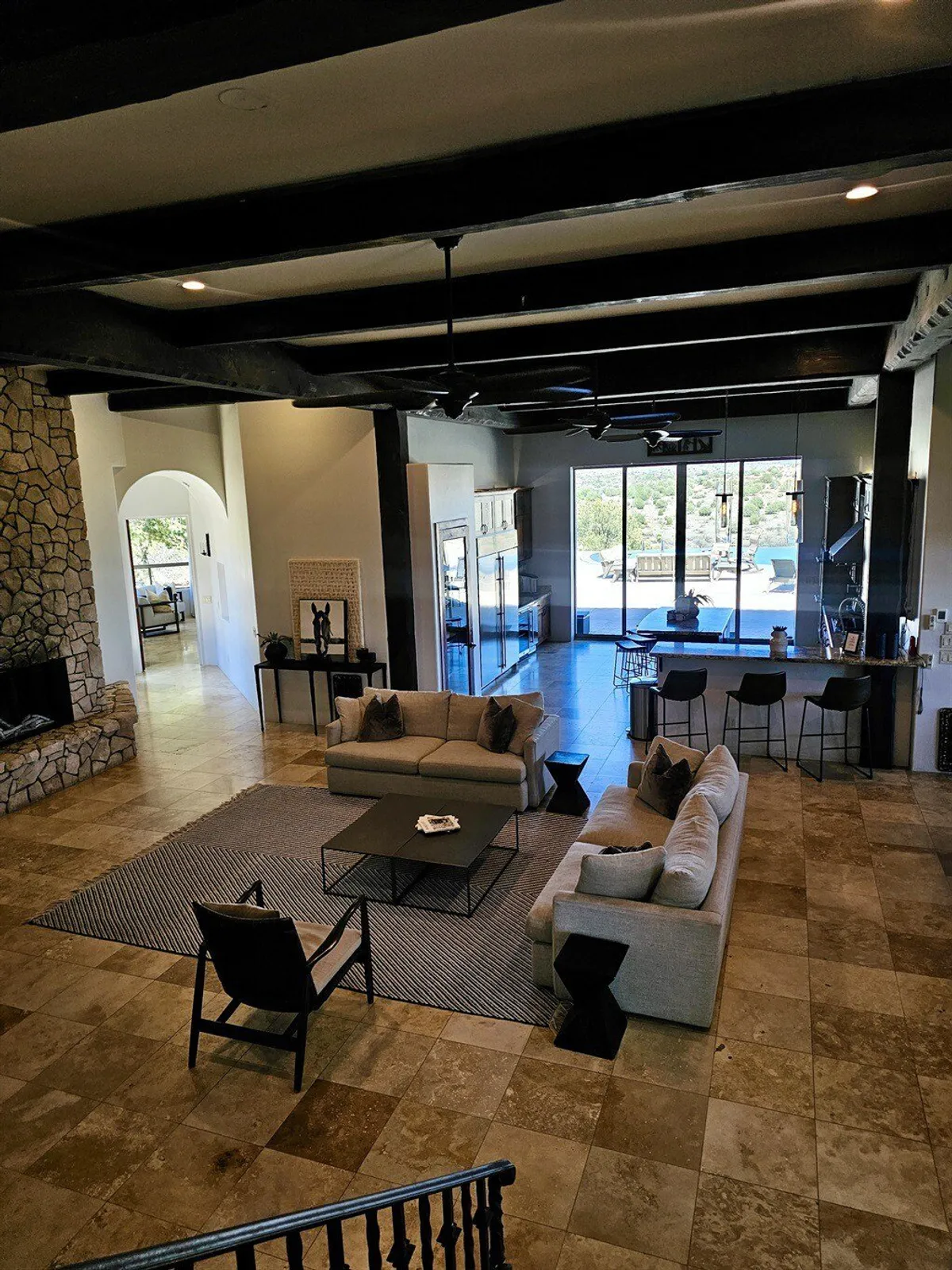 A bright, modern living area with a comfortable sofa, contemporary coffee table, and an open kitchen in the background. Large windows provide a stunning view, and the layout encourages both relaxation and group interaction.