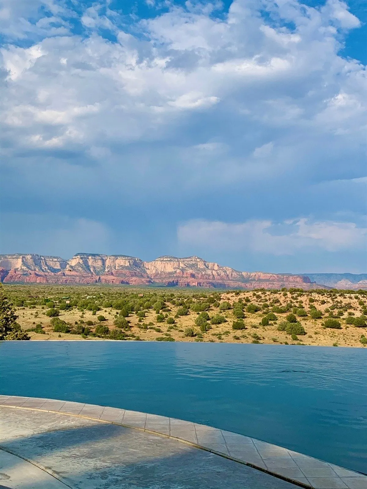 A tranquil infinity pool stretches toward an expansive view of Sedona’s distant mountain range and open sky. The serene water and natural horizon create a calming backdrop, perfect for moments of reflection, meditation, or group wellness activities.